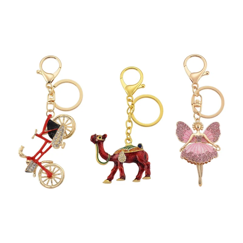 3er-Set emaillierte weiße, schwarze und rosa Kristall-Schlüsselanhänger mit Fahrrad, Kamel und geflügelter Ballerina, Legierung in Gelbgold